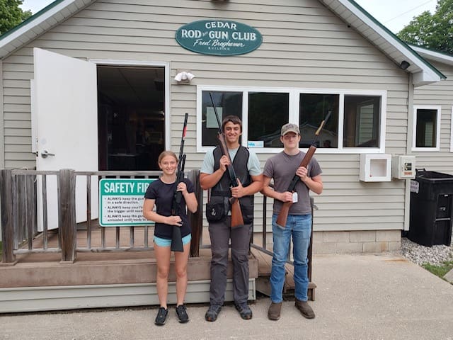 Three people holding guns in front of a building.
