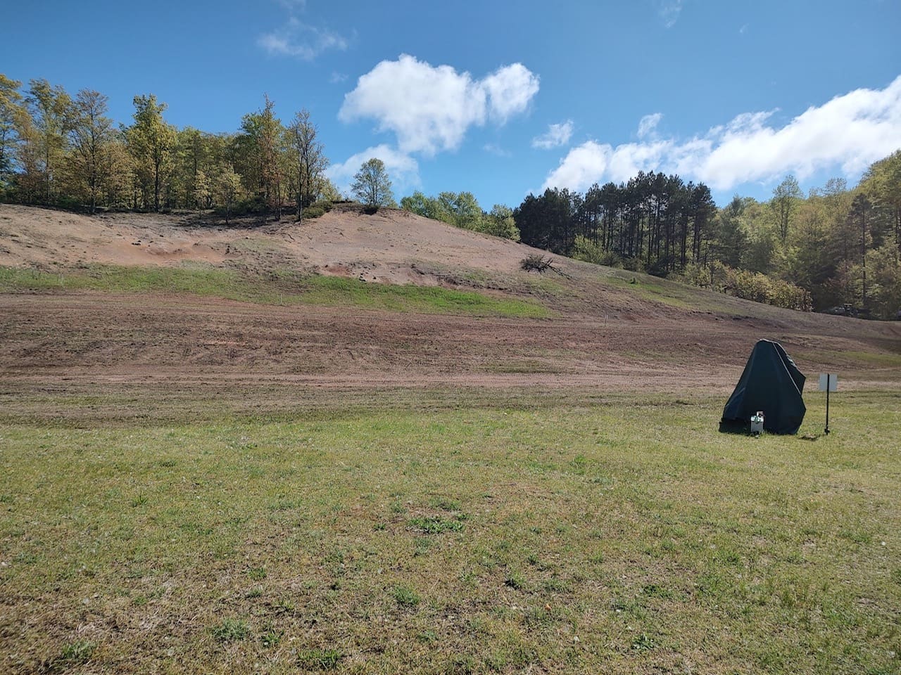 A large field with trees and hills in the background.